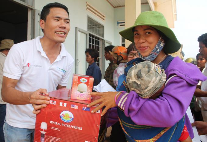 SC in Vietnam staff Tran Duc Manh (left) distributes water filters to a local resident in HBong commune, Chu Se district, Gia Lai province in the Central Highlands.  